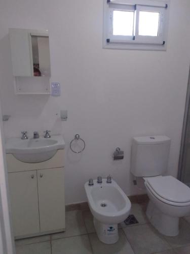 a white bathroom with a toilet and a sink at La Morada en Funes in Funes