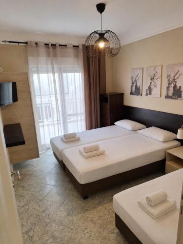 a bedroom with two beds and a chandelier at Sammys apartments in Nea Potidaea