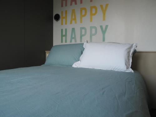 a bed with a happy happy pillow on it at Angèle - Relaxez-vous ! in La Roche-sur-Yon