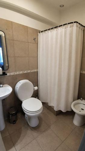 a bathroom with a toilet and a shower curtain at Apart Escobar in Belén de Escobar
