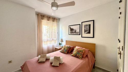 a bedroom with a bed with pink sheets and a window at Carihuela Playa Los Nidos 1 in Torremolinos