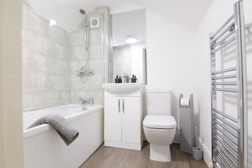 a white bathroom with a toilet and a sink at Coopers by the Coast in Selsey