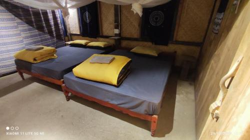 two beds in a small room with yellow sheets at Lũng Mười Homestay in Nà Giảo