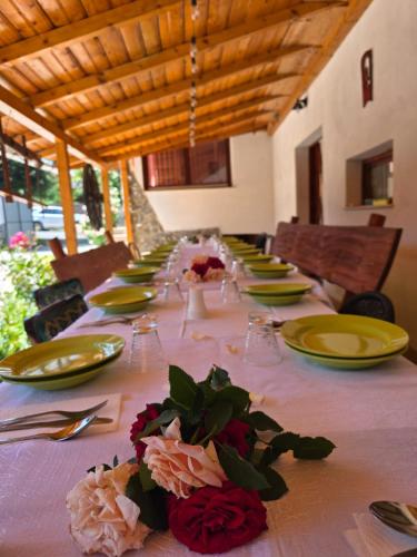 a long table with yellow plates and flowers on it at Casa de vacanta Marian in Sâmbăta de Sus