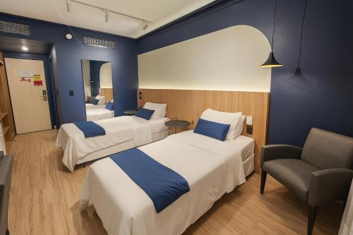 a hotel room with two beds and a chair at Swan Caxias do Sul in Caxias do Sul