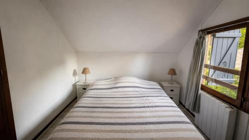 a bed in a white room with a window at La carrouere in Gujan-Mestras