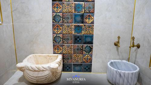a bathroom with a toilet and a tiled wall at MivanUrfa Otel in Urfa