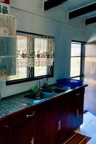 a kitchen with a sink and two windows at Tovuka House Scuba too in Rakiraki