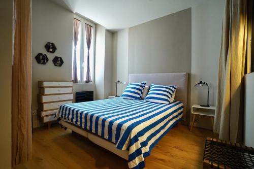 a bedroom with a bed with blue and white striped sheets at T2 intra muros clim et cour ombragée in Avignon