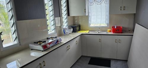 a kitchen with white cabinets and a sink and windows at Haven Apartments- Nadi in Nadi