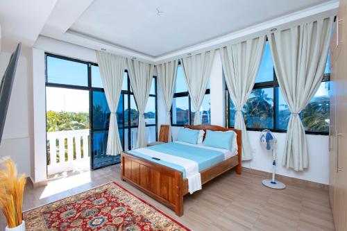 a bedroom with a bed and large windows at Diani Luxe Villa in Galu