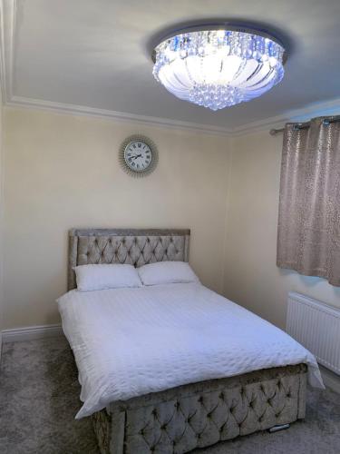 a bedroom with a large bed with a chandelier at Williton Guest House in Luton