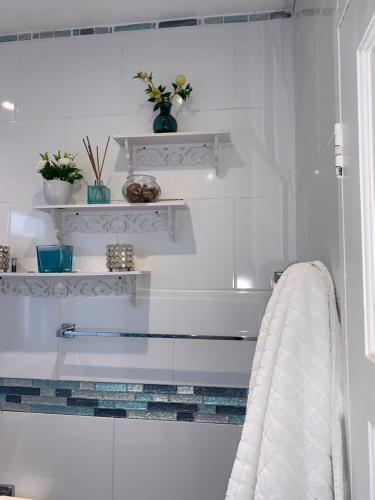 a white bathroom with white shelves and a towel at Williton Guest House in Luton