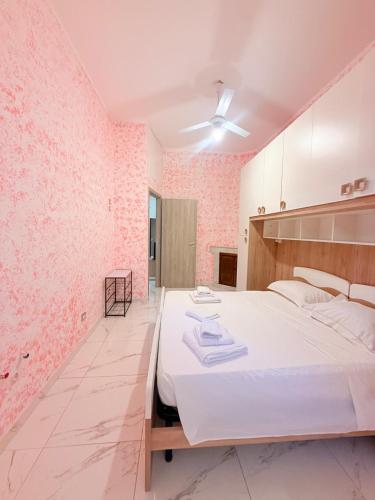 a bedroom with a white bed and a pink wall at Via Acquedotto 54 in Olbia