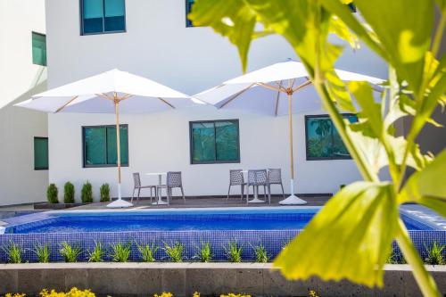 a swimming pool with chairs and umbrellas next to a building at Hm Express in Colima