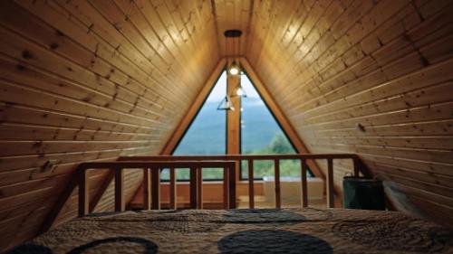 a bed in a wooden room with a large window at Kesane Cottages in Racha in Oni