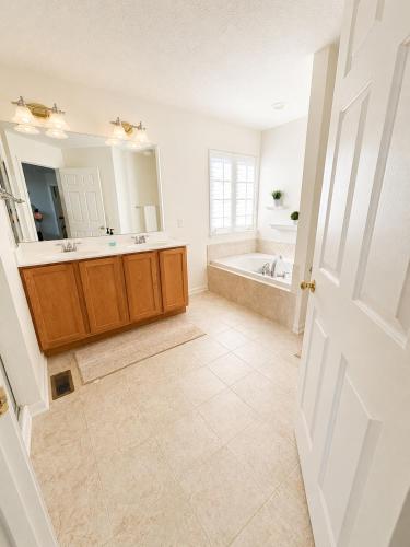 a bathroom with a tub and a sink and a mirror at 4BR Home with Private Cinema in West Henrietta