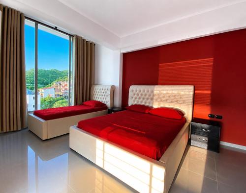 two beds in a room with a red wall at Hotel Albsin in Vlorë