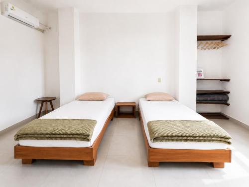 two beds in a room with white walls at Galápagos Downtown Suite in Puerto Ayora