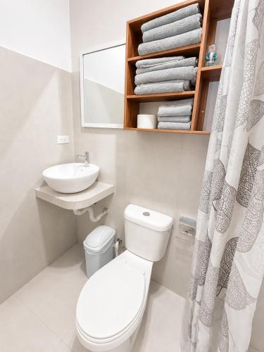 a white bathroom with a toilet and a sink at Galápagos Downtown Suite in Puerto Ayora