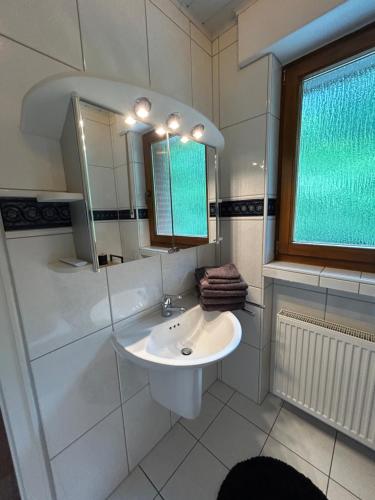 a white bathroom with a sink and a mirror at Haus am Skywalk 3L in Beverungen