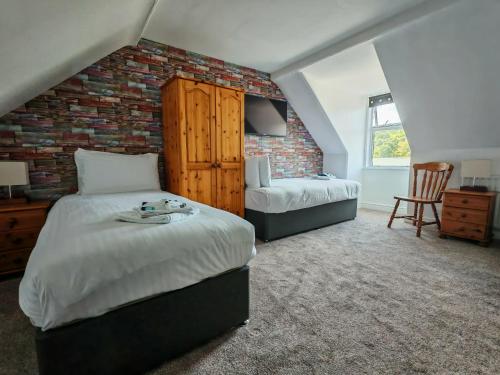 a bedroom with two beds and a brick wall at The Grapes Hotel in Newcastleton