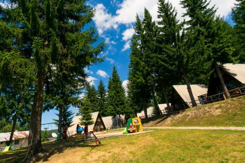 a park with a playground with trees and houses at Romantica Forest Guest House in Dospat