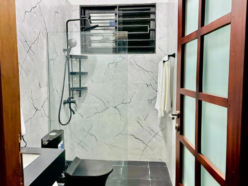 a bathroom with a shower and a toilet and a sink at Shubbys Villa in Dar es Salaam
