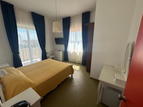 a hotel room with a bed and two windows at Hotel e Residence Il Faro Acciaroli in Acciaroli