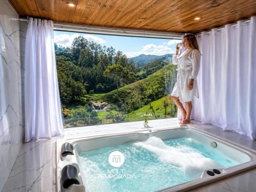 a woman standing in a bath tub in a window at Pousada Dona Teresinha com Piscina Aquecida - São Bonifácio/SC in São Bonifácio