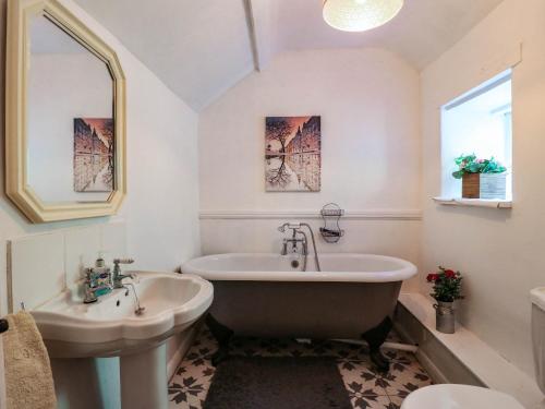 a bathroom with a tub and a sink at Jasmine Cottage in Matlock