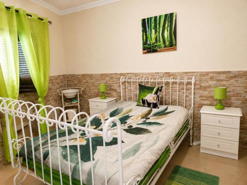 a bedroom with a white bed and green curtains at Casa Bia Olívia in Albernoa