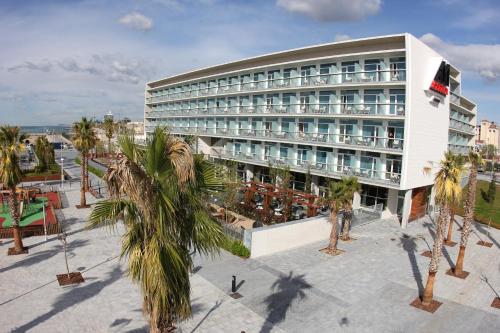 a large building with palm trees in front of it at Atenea Port Barcelona Mataró in Mataró