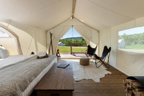 a bedroom with a tent with a bed and two chairs at Under Canvas White Mountains in Dalton