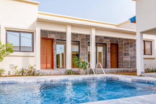 a home with a swimming pool in front of a house at Villas HouN Assinie in Mafia