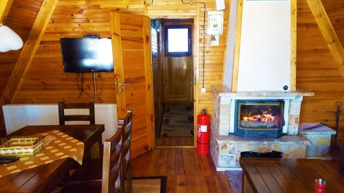 a living room with a fireplace in a log cabin at Romantica Forest Guest House in Dospat