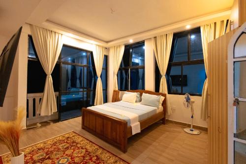 a bedroom with a bed in a room with windows at Diani Luxe Villa in Mombasa