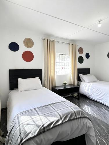 a white bedroom with two beds and a window at The Tiny House - Solwezi in Solwezi