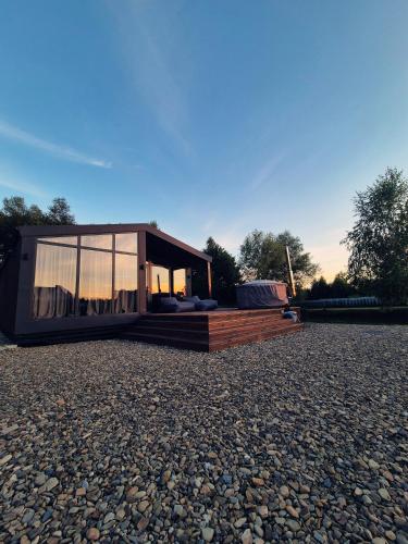 a small house with a large window on a gravel yard at SHKLO Lake&SPA in Shklo