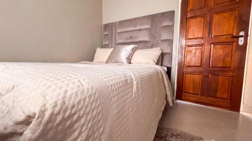 a bedroom with a bed with white sheets and a wooden door at SAOB Property- South A in Germiston