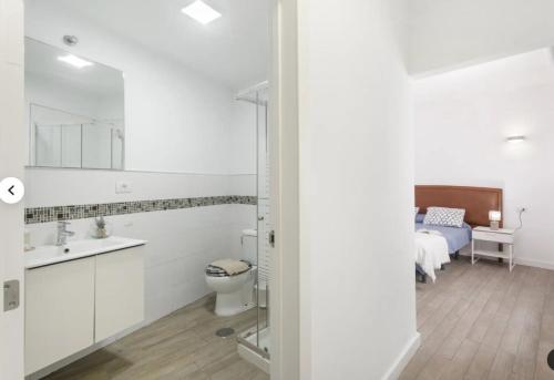 a bathroom with a sink and a toilet and a bed at Habitaciones IFAE in Alcalá