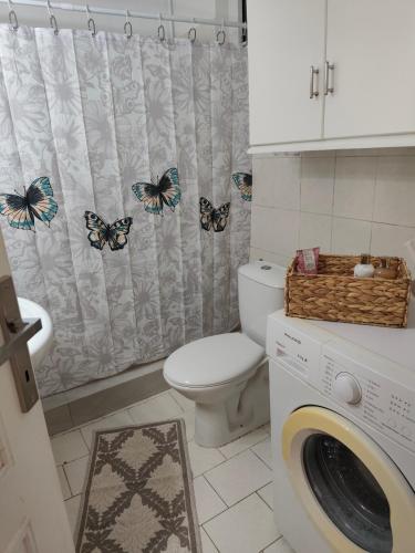 a bathroom with a toilet and a shower curtain with butterflies at Panora House in Kefalos