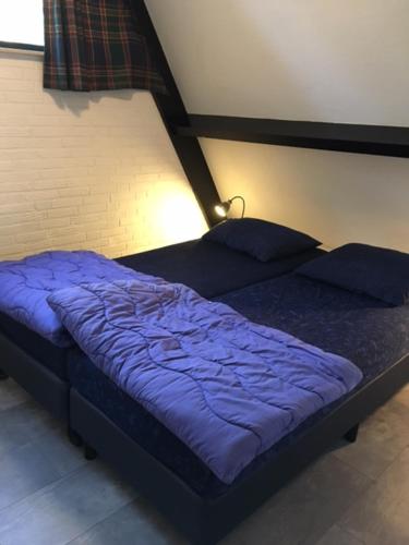 uma cama com lençóis e almofadas azuis num quarto em Vakantiepark Vosseven 77 em Stramproy