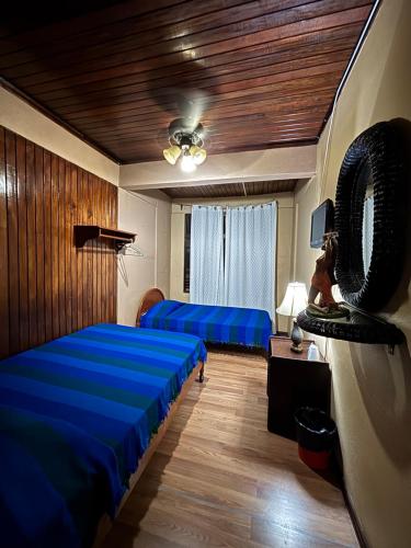 a bedroom with two beds and a wooden ceiling at Charly's Place in Alajuela