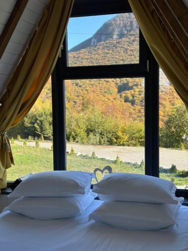 ein Bett mit weißen Kissen in einem Zimmer mit Fenster in der Unterkunft Wild Hill Frames in Holbav