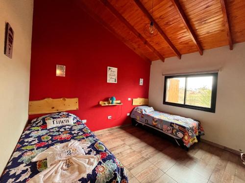 a bedroom with two beds and a red wall at Complejo de Cabañas Los 2 Soles 9 in Los Reartes