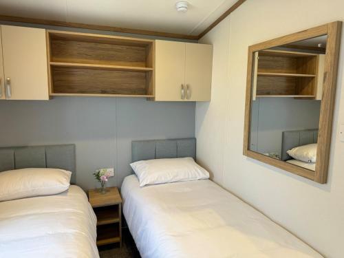 two beds in a room with a mirror and cabinets at Luxury lodge Henley in Cherry Burton