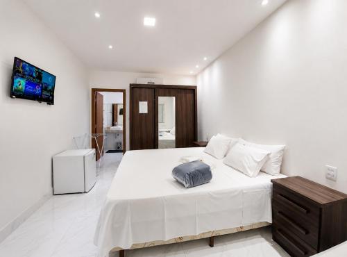 a white bedroom with a large bed and a tv at Suíte com Jacuzzi Vista de Escarpas 3 in Capitólio
