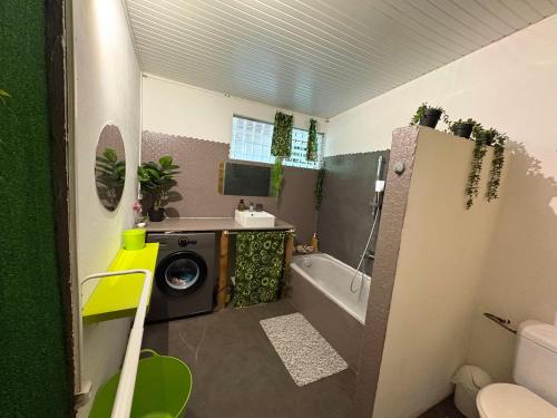 a bathroom with a tub and a washing machine at Maison créole avec piscine et accès à la rivière in Lamentin