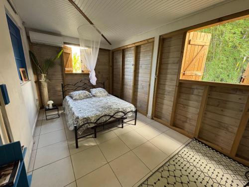a bedroom with a bed in a room with wooden walls at Maison créole avec piscine et accès à la rivière in Lamentin